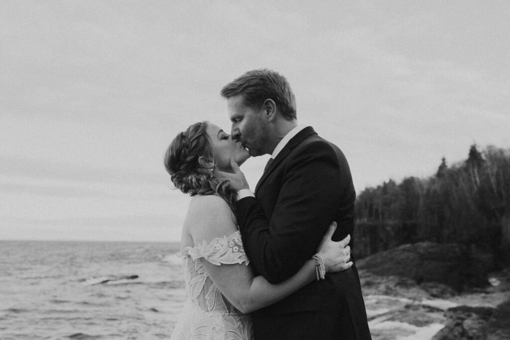 black and white portrait of a couple kissing on the black rocks