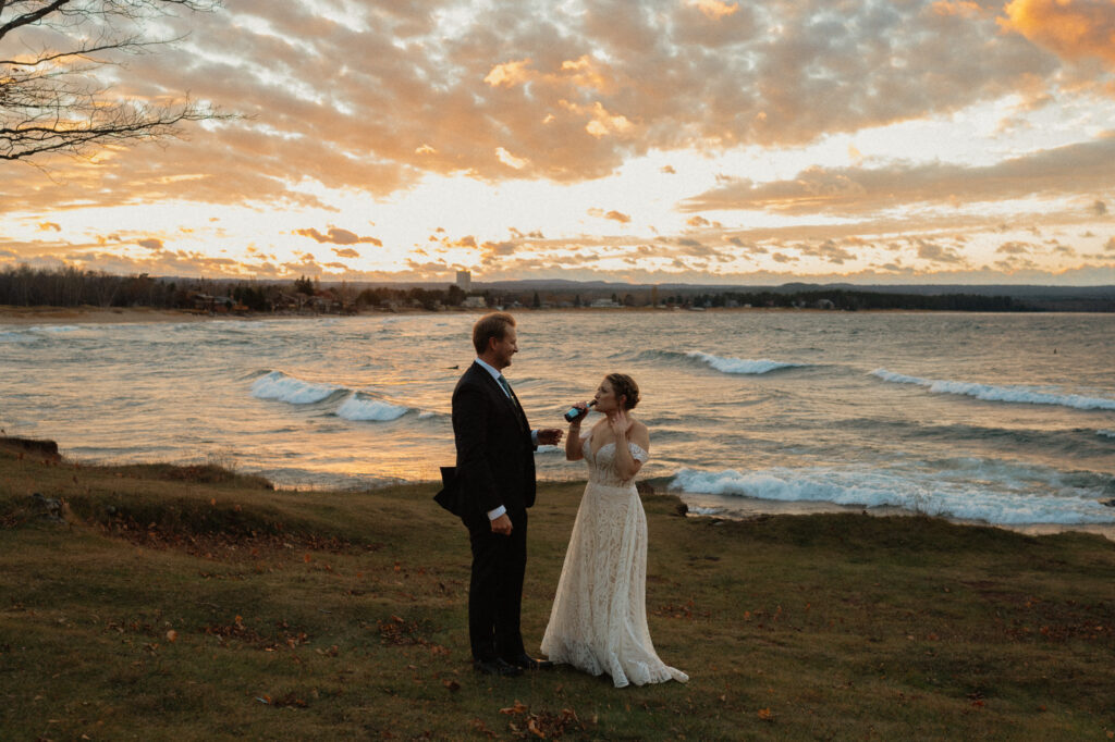 bride drinks champagne at sunset in marquette elopement