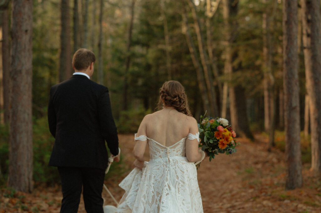 couple walking in woods during wedding